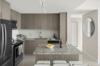 A modern kitchen with a granite countertop and stainless steel appliances.